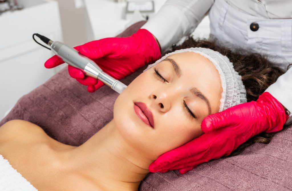Woman at an aesthetician receiving microneedling treatment to rejuvenate her skin