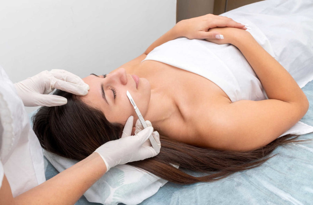 A woman getting a dermaplaning treatment from a certified aesthetician to gently exfoliate her skin