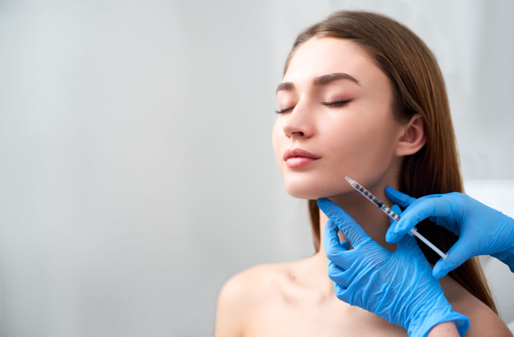 A woman receiving dermal fillers in her jawline from her aesthetician to sculpt and define the chin and jawline.