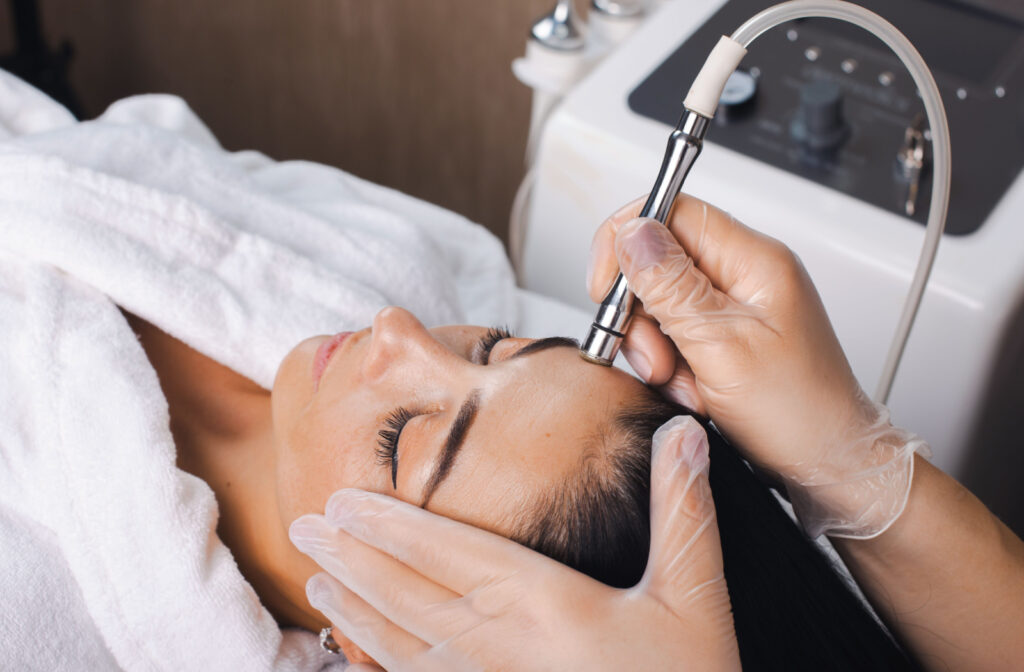 A woman receiving a microdermabrasion treatment from an aesthetician.