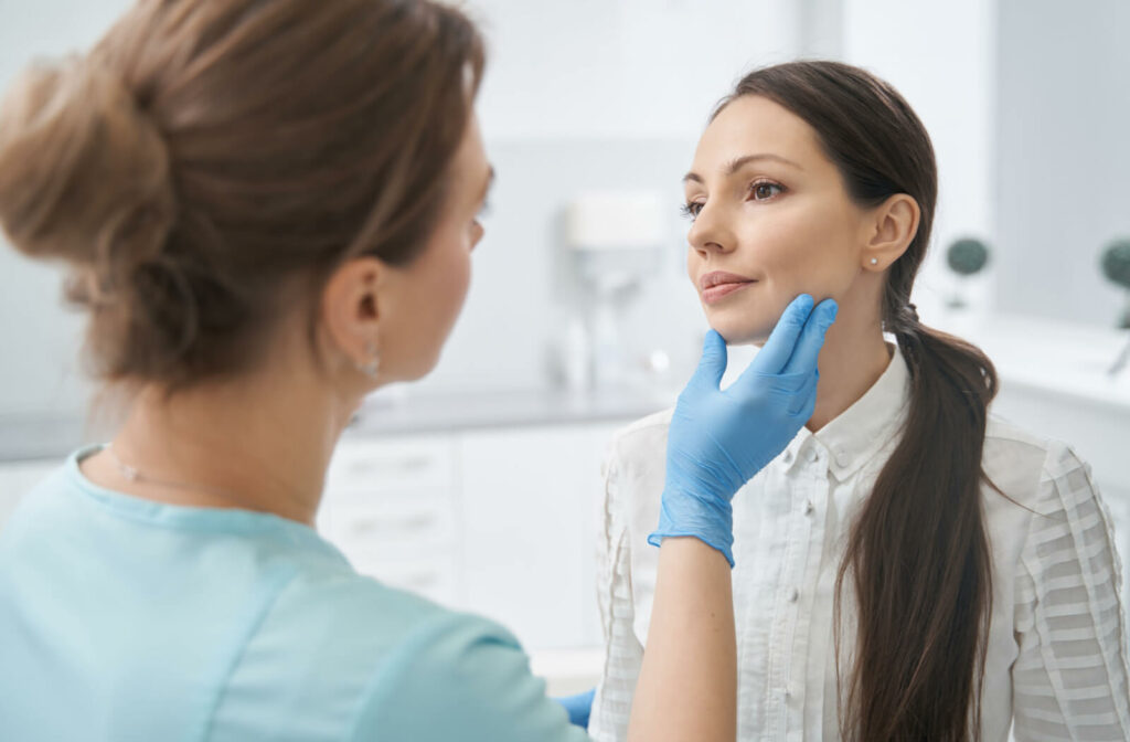 An aesthetician holds her client's face while looking at her skin.