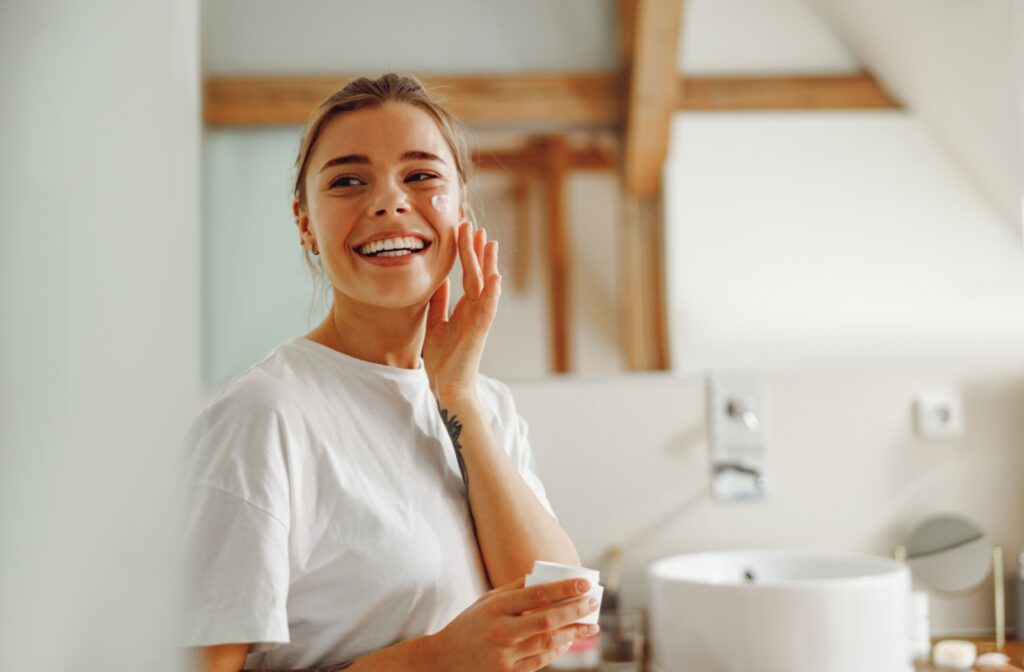 After her dermaplaning session, a young woman applies her skincare to experience better product absorption.