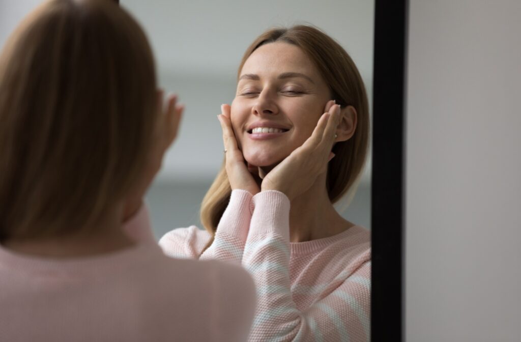 An adult touching their cheeks and admiring the results of their professional facial in the mirror.