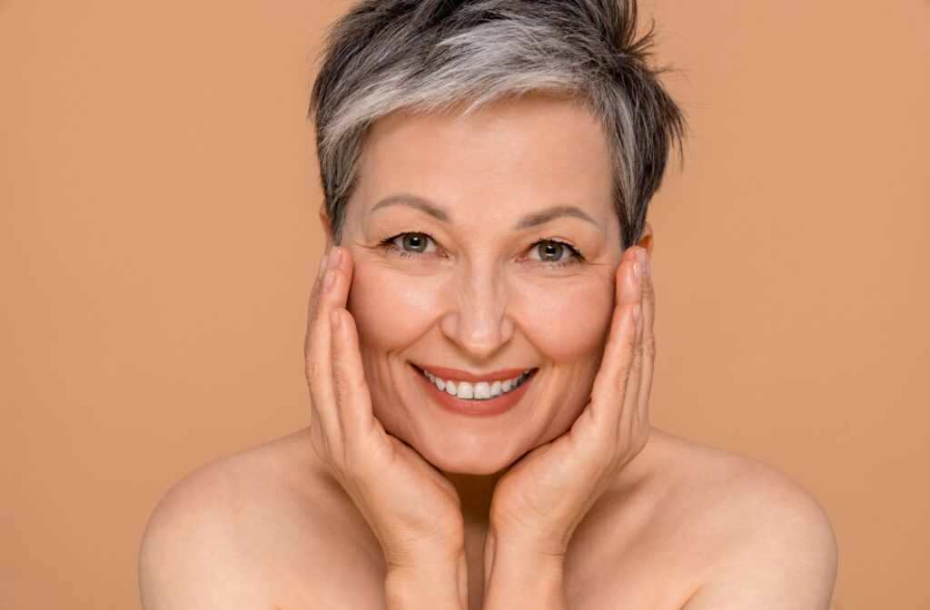 A person smiling while cupping their cheeks after having a Botox treatment.