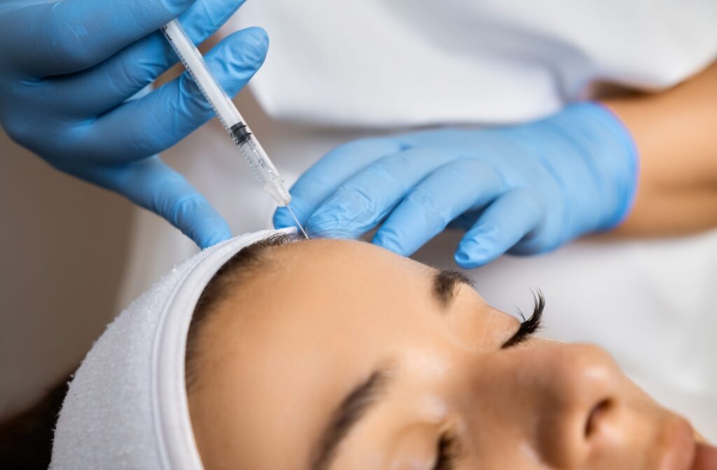 A cosmetic nurse injector applying Botox treatment to a person's forehead.