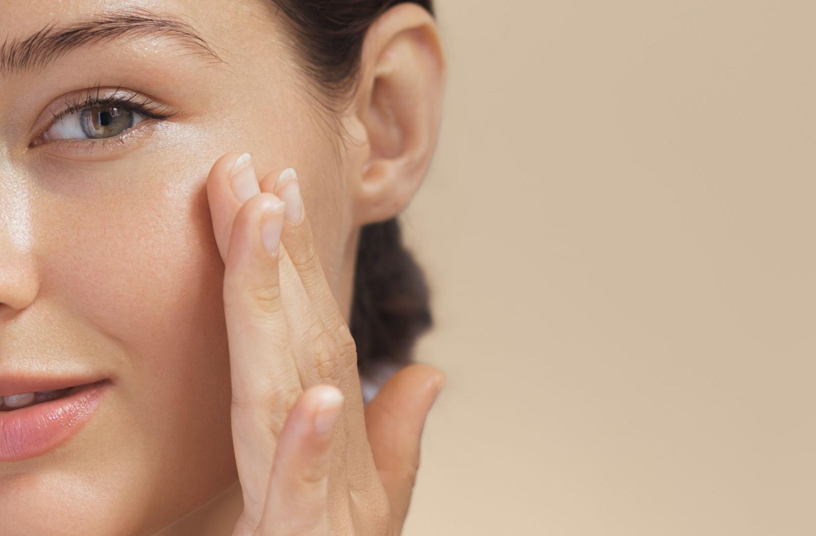 A person with perfect skin lightly touching their skin