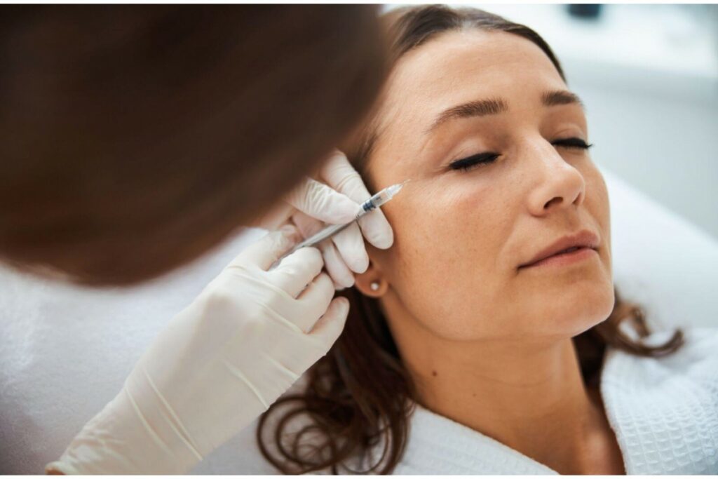 A practitioner carefully injects Botox around a patient's eyes.